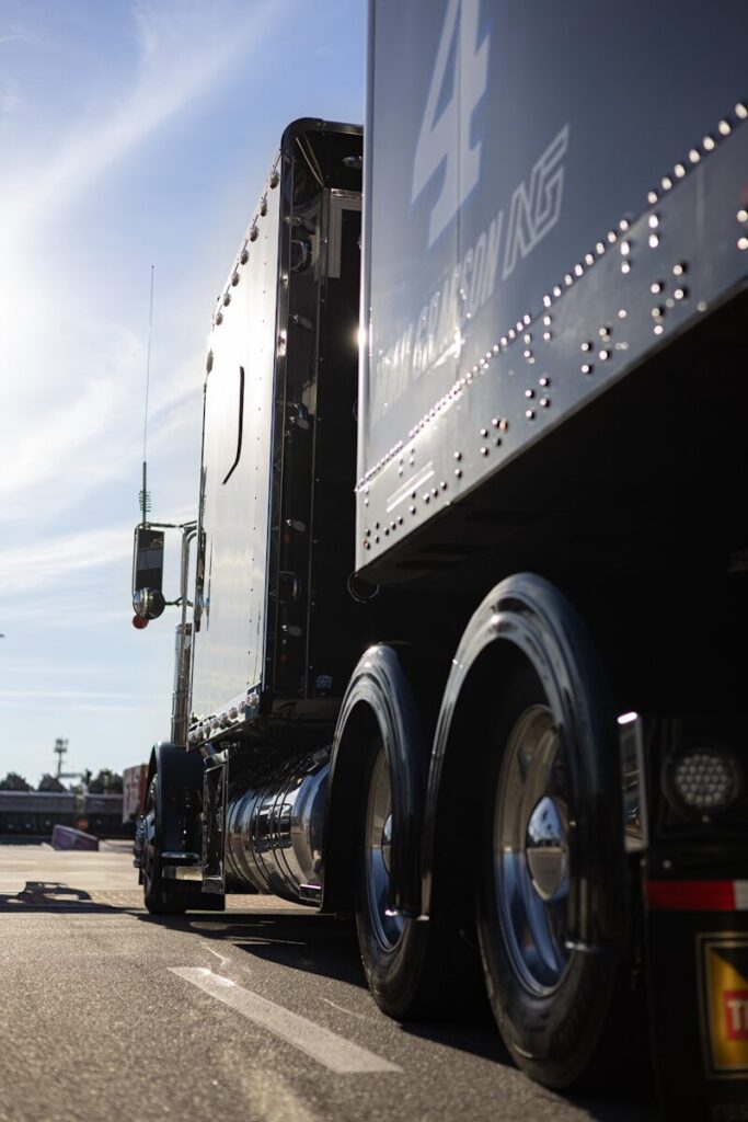 oil-1 A black semi-truck with a trailer drives on a road.