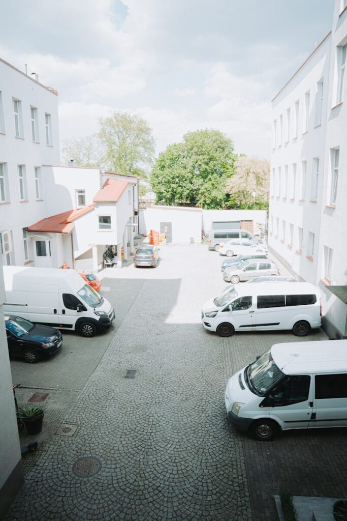 automotive White vans parked in a cobblestone courtyard surrounded by buildings.